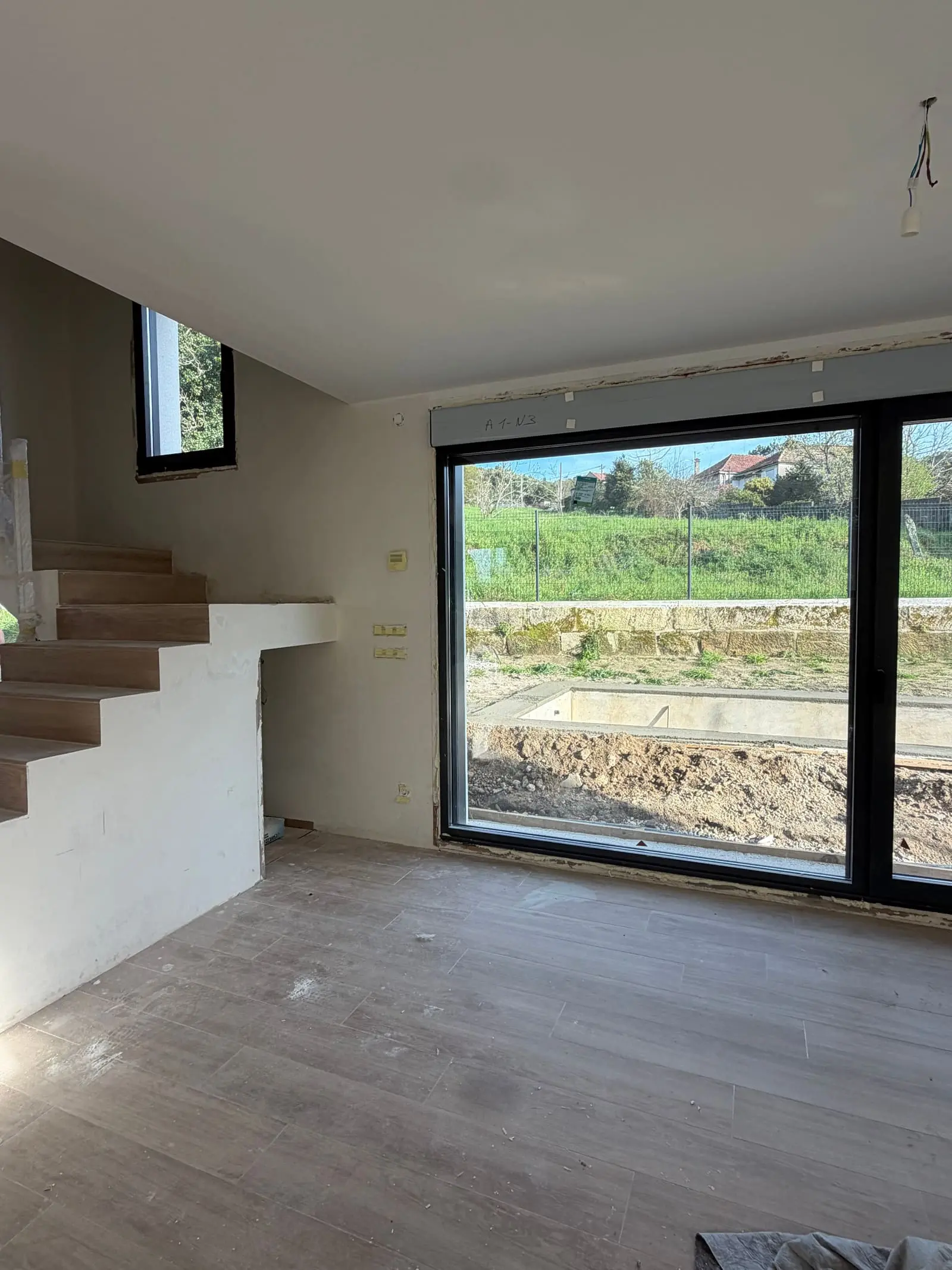 La escalera interior terminada, con el ventanal al jardín al fondo